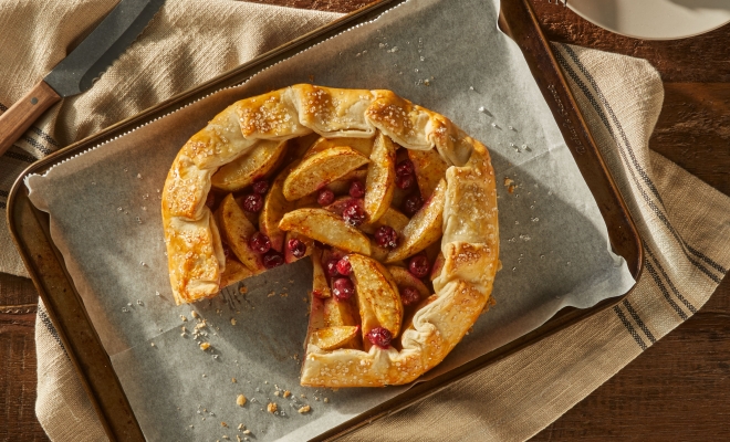 Apple and cranberry tart sitting on a parchment lined baking sheet