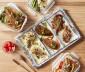 A table with chicken, meat, and other foods on a tray with aluminum foil